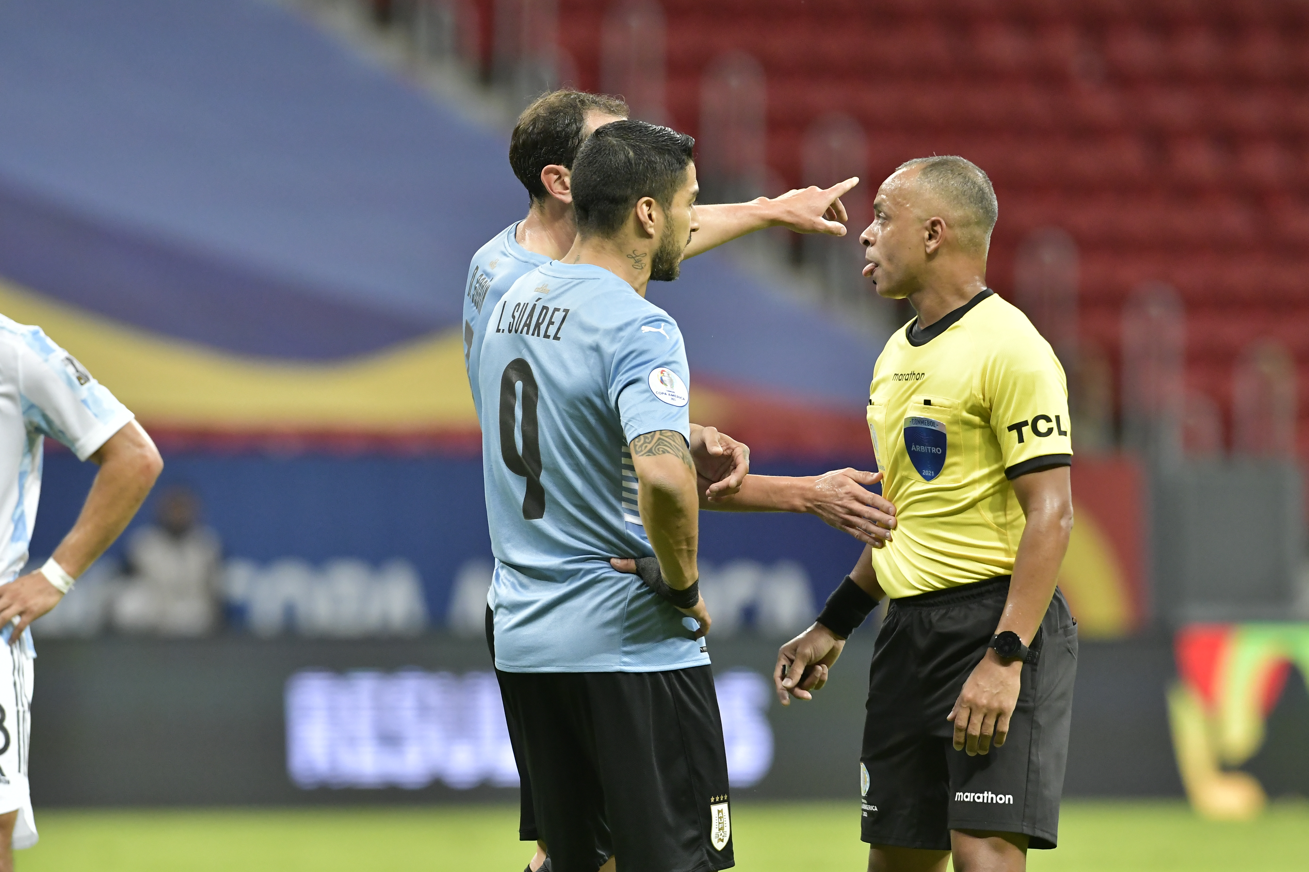 Luis Suárez y Diego Godín dialogan con el árbitro principal Wilton Sampaio.
