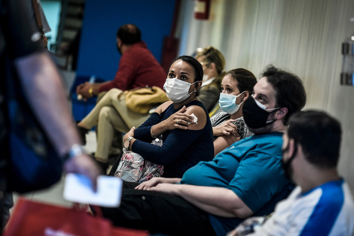 Centro de vacunación Covid 19 - Pacientes sentados en sala de espera, algunos ya vacunados y otros esperando a ser vacunados.