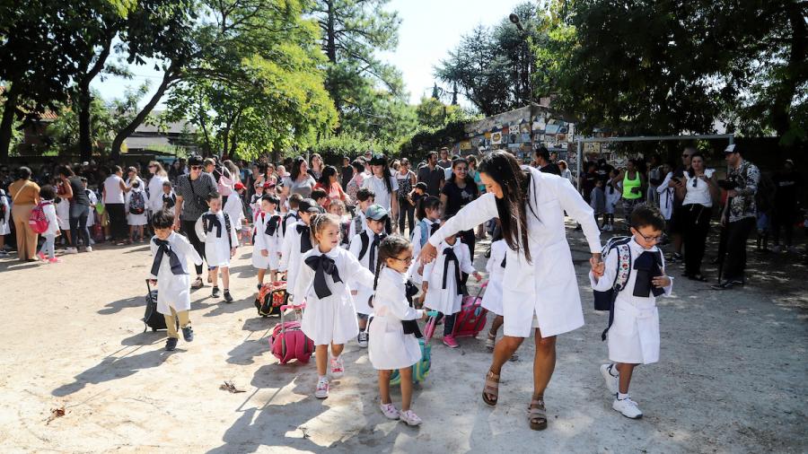 Maestra dirigiendo a sus alumnos por el patio de una escuela