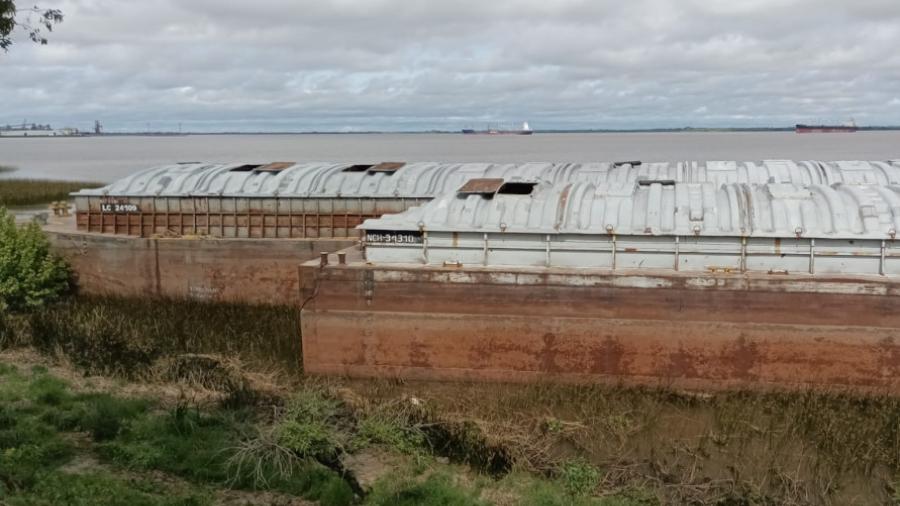 Dos de las cinco barcazas   sobre la costa de Brisas del Uruguay (Foto APU.uy)