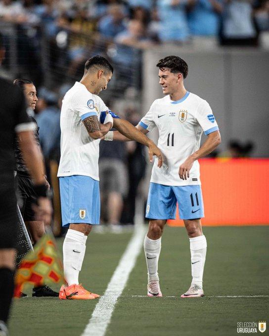 Pellistri le entrega de parte de Valverde la cinta de capitán a Suárez. Foto @uruguay